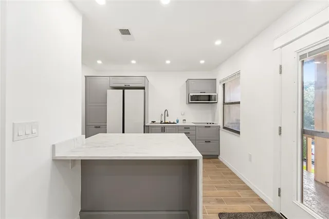 a large white kitchen with sink a refrigerator and white cabinets