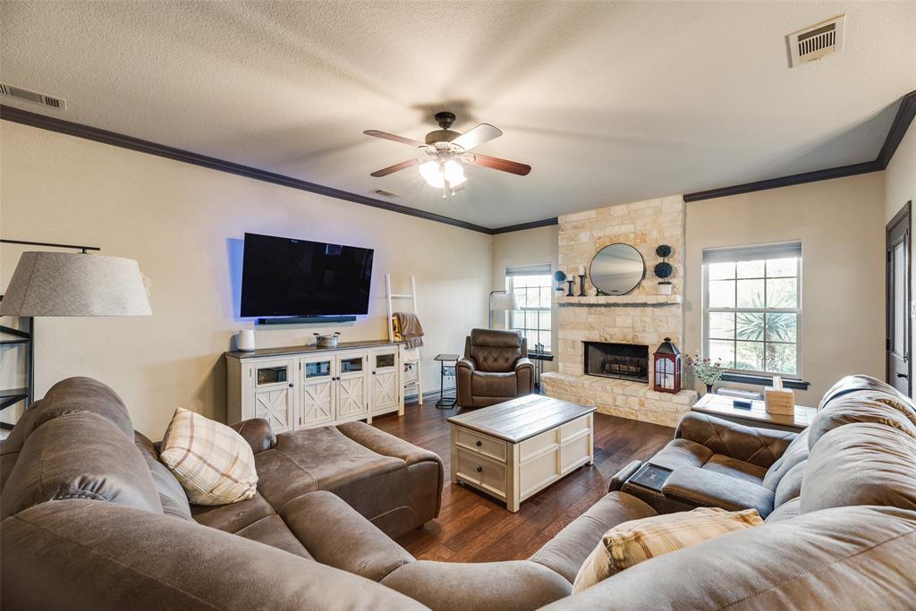1132 Chartres Street Kaufman, TX 75142 - Photo 4 of 25 Spacious living area featuring rich wood-finish flooring and a stone-clad fireplace