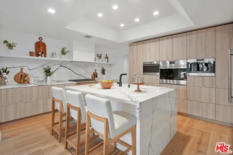 a kitchen with a sink a stove a refrigerator and white cabinets with wooden floor