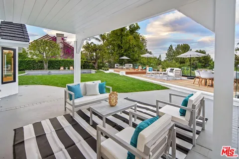 a view of a patio with a dining table and chairs with a small yard