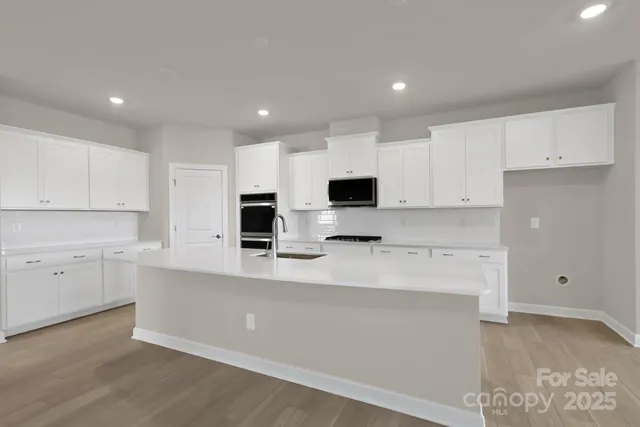 a large kitchen with stainless steel appliances a sink a stove and a refrigerator