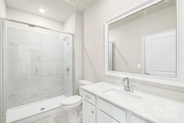 a spacious bathroom with a granite countertop sink a mirror and a toilet