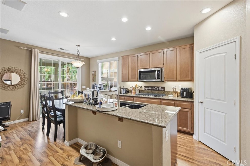 32623 Ritter Court Temecula, CA 92592 - Photo 17 of 40 a kitchen with stainless steel appliances granite countertop a stove top oven a sink dishwasher a dining table and chairs with wooden floor