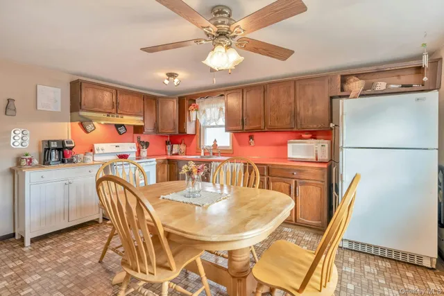a dining room with stainless steel appliances a table chairs and a refrigerator