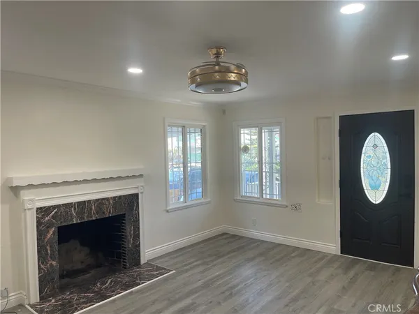 an empty room with wooden floor a fireplace and windows