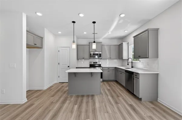 a large kitchen with stainless steel appliances granite countertop a sink a stove and a wooden floors