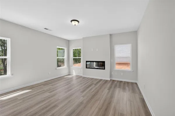 a view of an empty room with a window and wooden floor