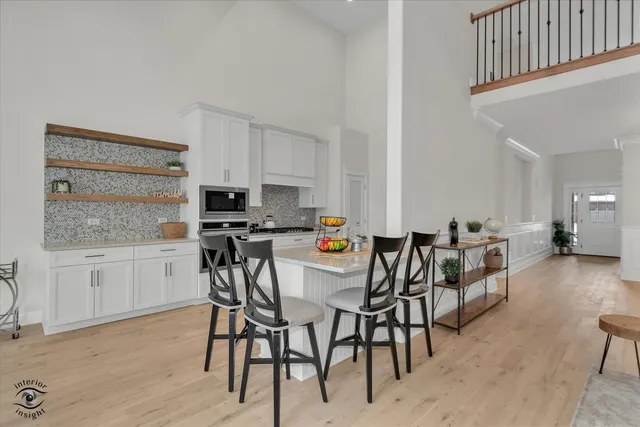 a kitchen with stainless steel appliances kitchen island granite countertop a table chairs stove and white cabinets