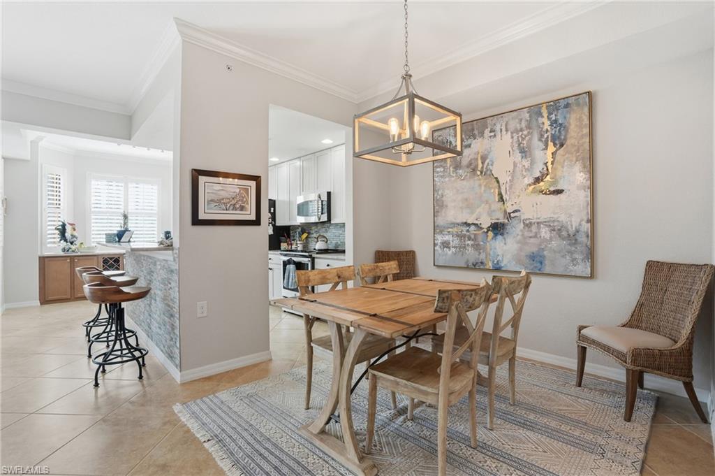 9715 Acqua Court, Unit 113 Naples, FL 34113 - Photo 11 of 31 Dining room featuring light tile patterned floors, crown molding, and a chandelier