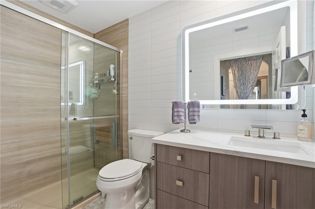 9715 Acqua Court, Unit 113 Naples, FL 34113 - Photo 19 of 31 Bathroom with vanity, a shower stall, tile walls, and decorative backsplash