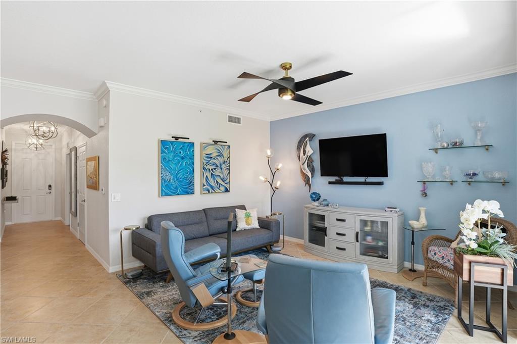 9715 Acqua Court, Unit 113 Naples, FL 34113 - Photo 4 of 31 Living room featuring arched walkways, crown molding, light tile patterned floors, suspended lighting, and ceiling fan