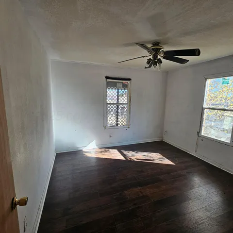 a view of an empty room with a window and wooden floor