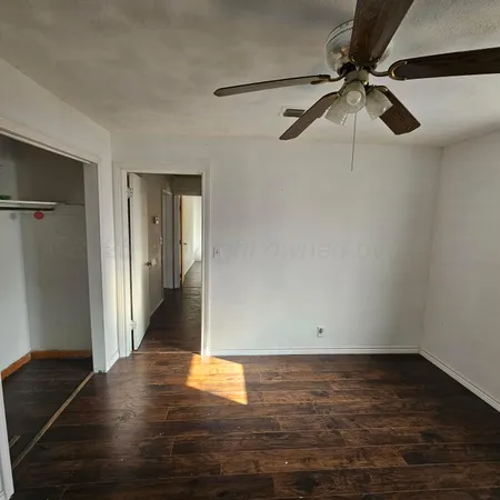 a view of a room with wooden floor a ceiling fan and window
