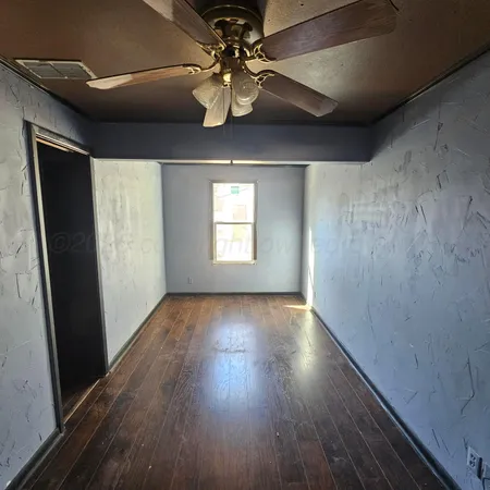 en empty room with wooden floor and windows