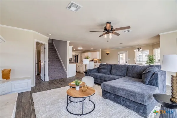 a living room with furniture and a dining table with wooden floor