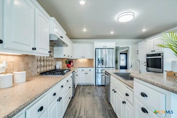 a kitchen with granite countertop a sink stove and refrigerator