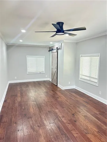 a view of empty room with wooden floor and fan