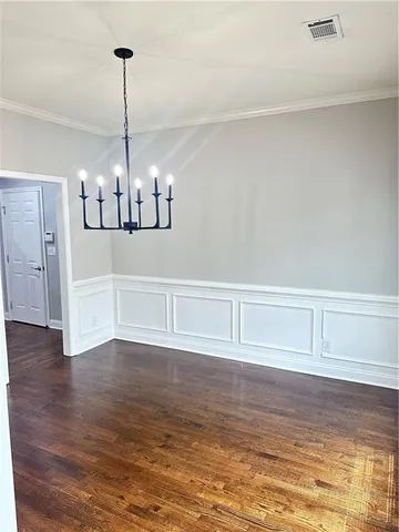 a view of an empty room with wooden floor chandelier