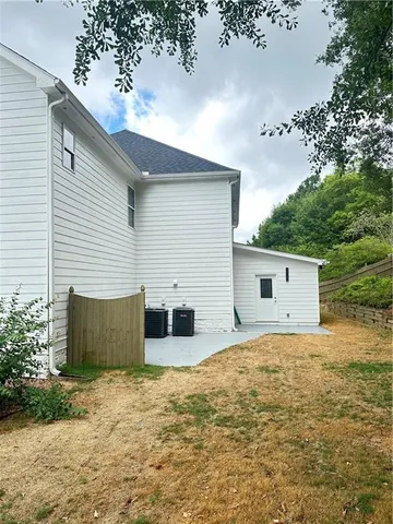 a backyard of a house with wooden fence and a tree