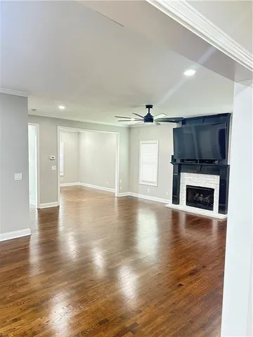 a view of a livingroom with a fireplace a ceiling fan and windows