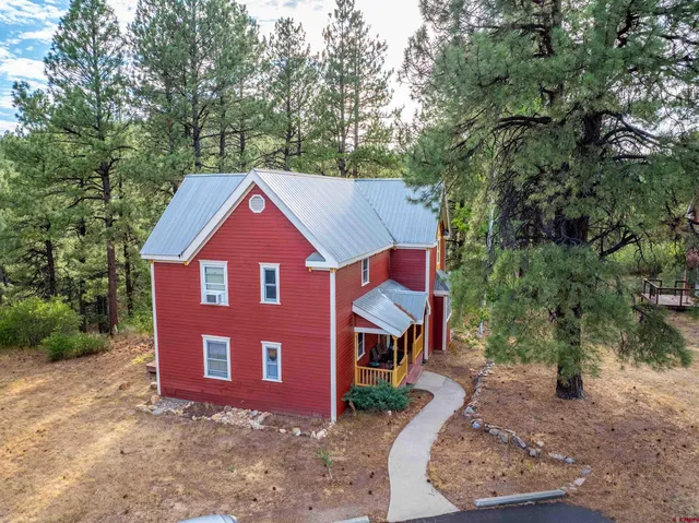 a view of a house with a yard plants and large tree