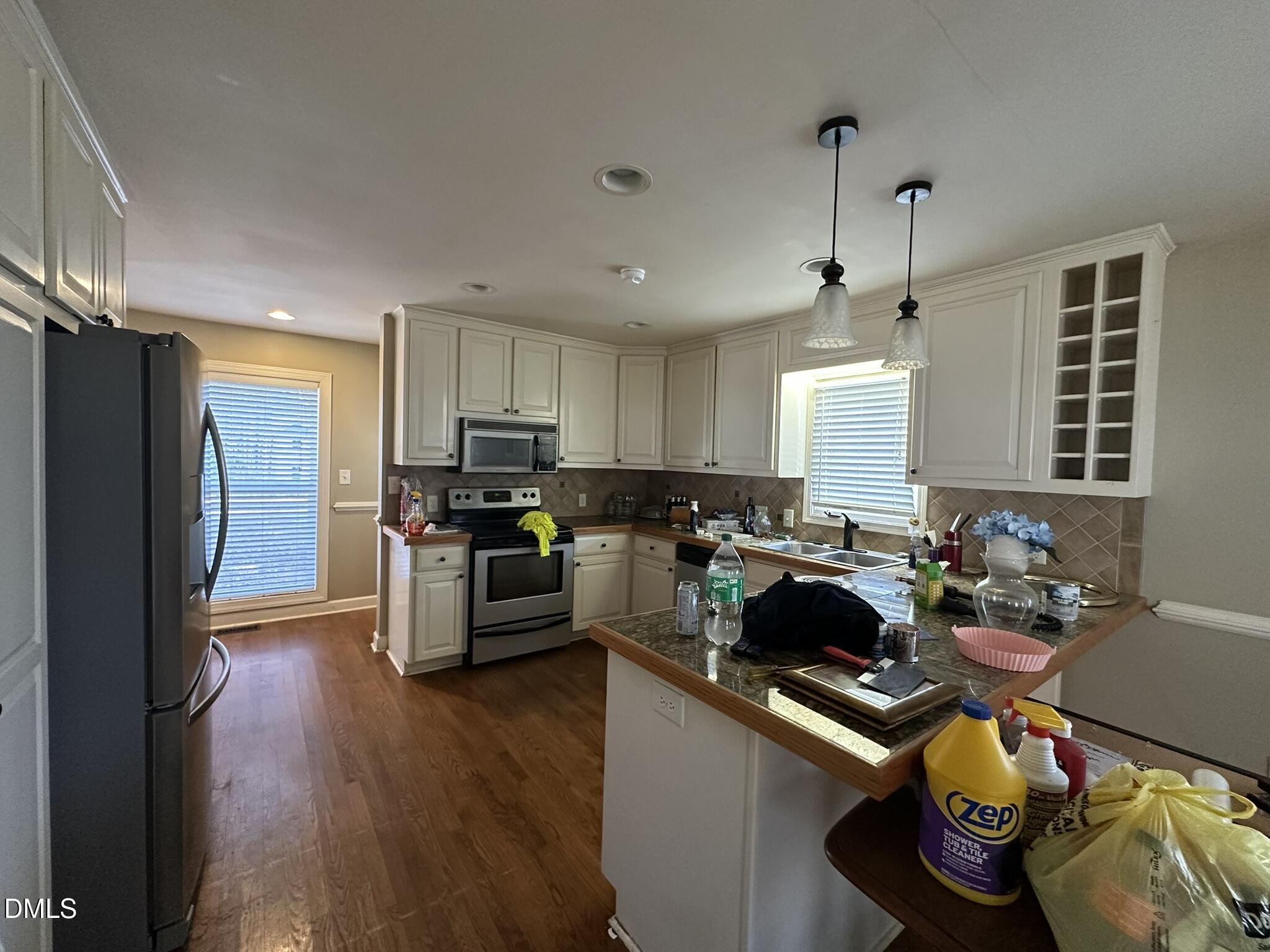 7208 Eastover Drive Raleigh, NC 27603 - Photo 12 of 41 a kitchen with stainless steel appliances granite countertop a refrigerator a sink dishwasher a stove and a dining table with wooden floor