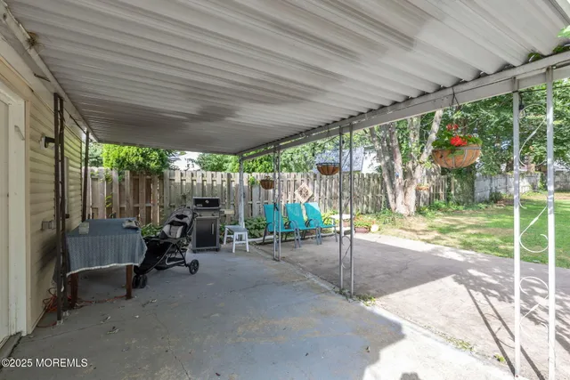 a view of a patio with table and chairs and floor to ceiling window with wooden fence