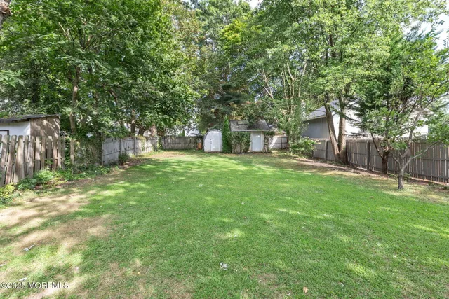 a view of a backyard with large trees and wooden fence