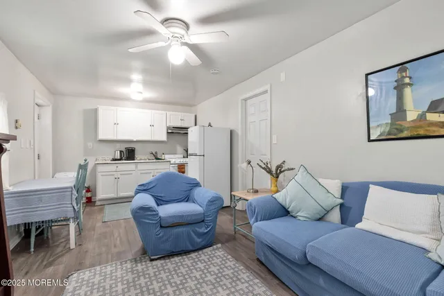 a living room with furniture and a dining table with kitchen appliances