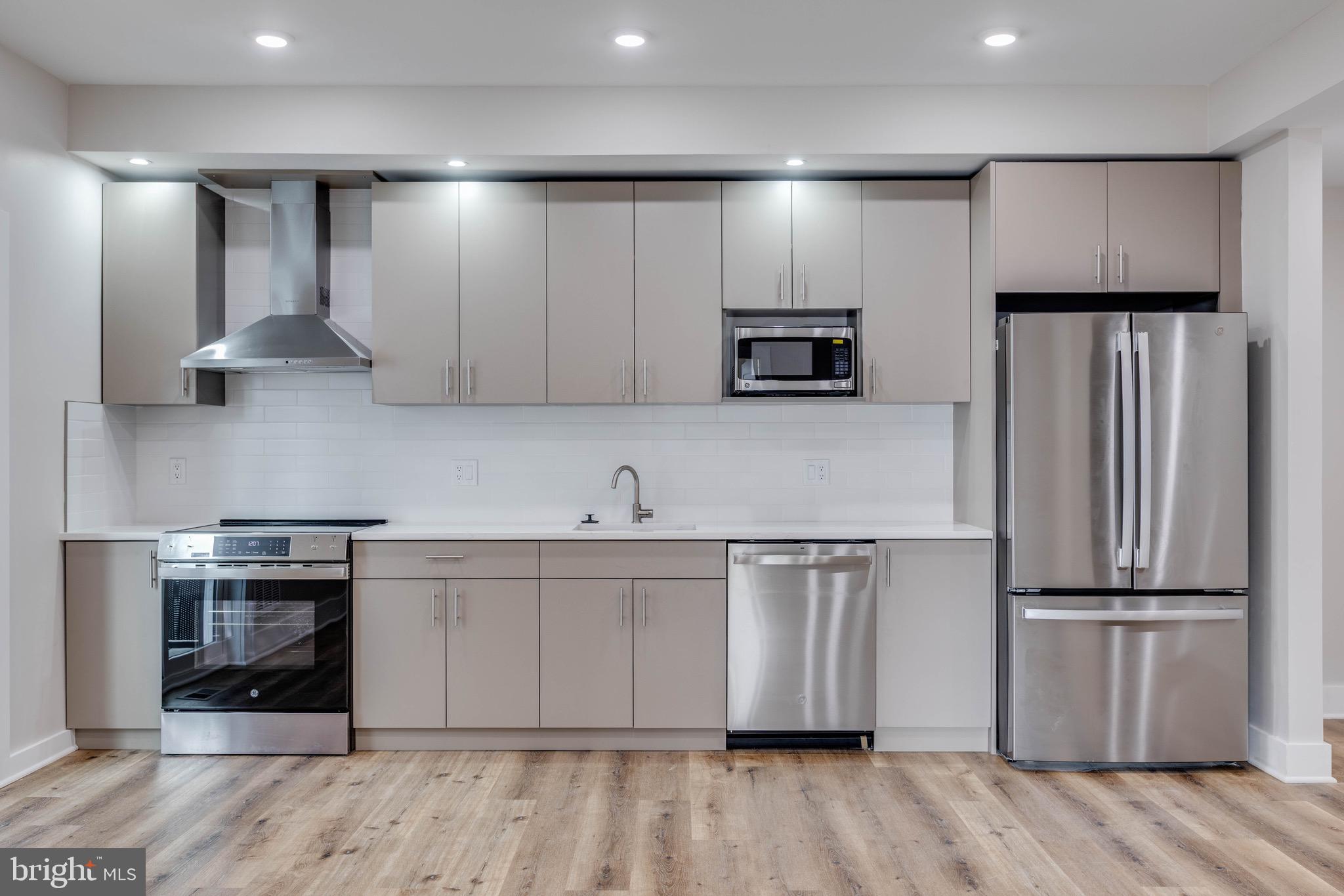 1434 Parrish Street, Unit B Philadelphia, PA 19130 - Photo 3 of 17 a kitchen with kitchen island white cabinets and stainless steel appliances
