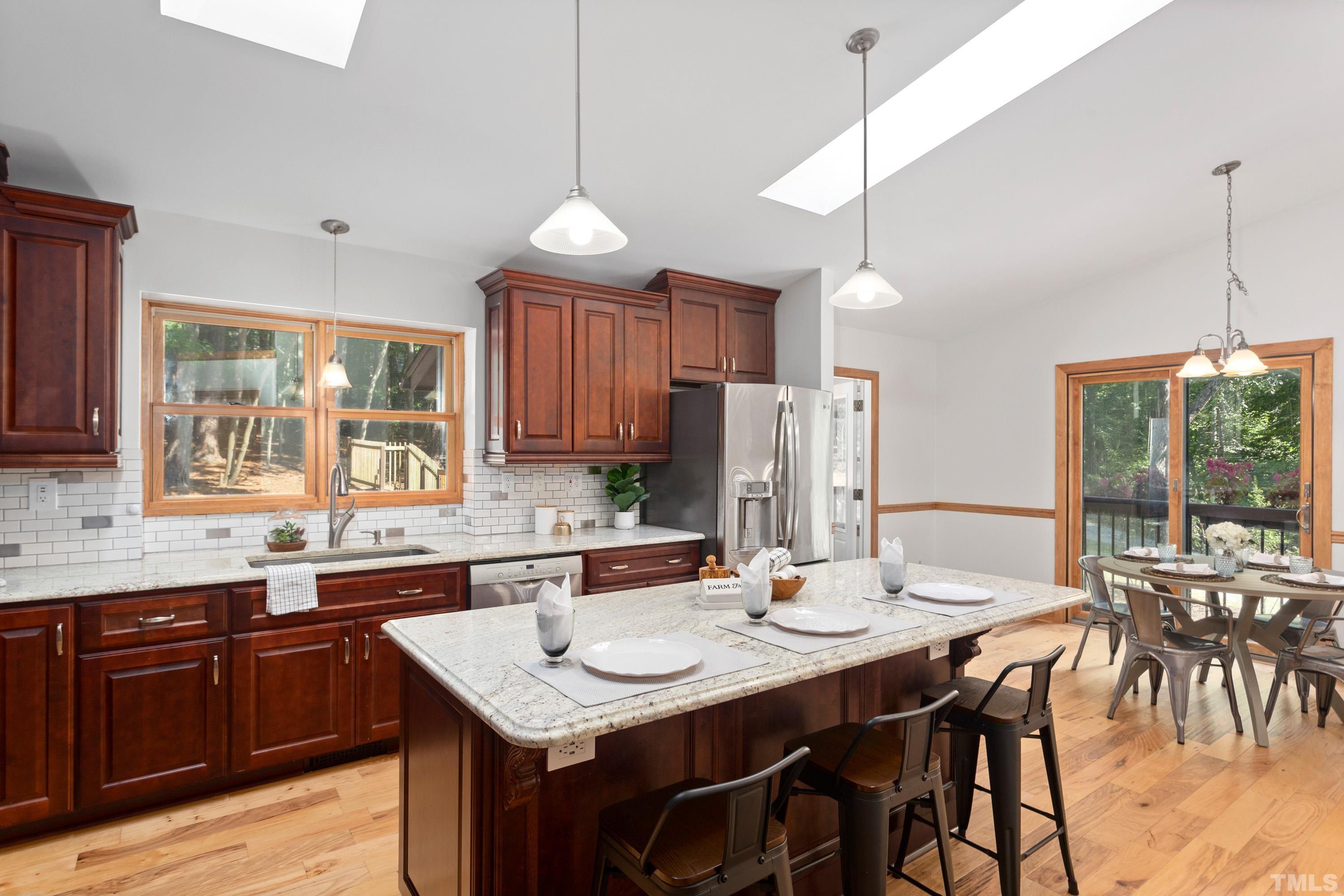 2600 Ferrand Drive Durham, NC 27705 - Photo 11 of 67 a kitchen with stainless steel appliances kitchen island granite countertop a table chairs in it and wooden floors