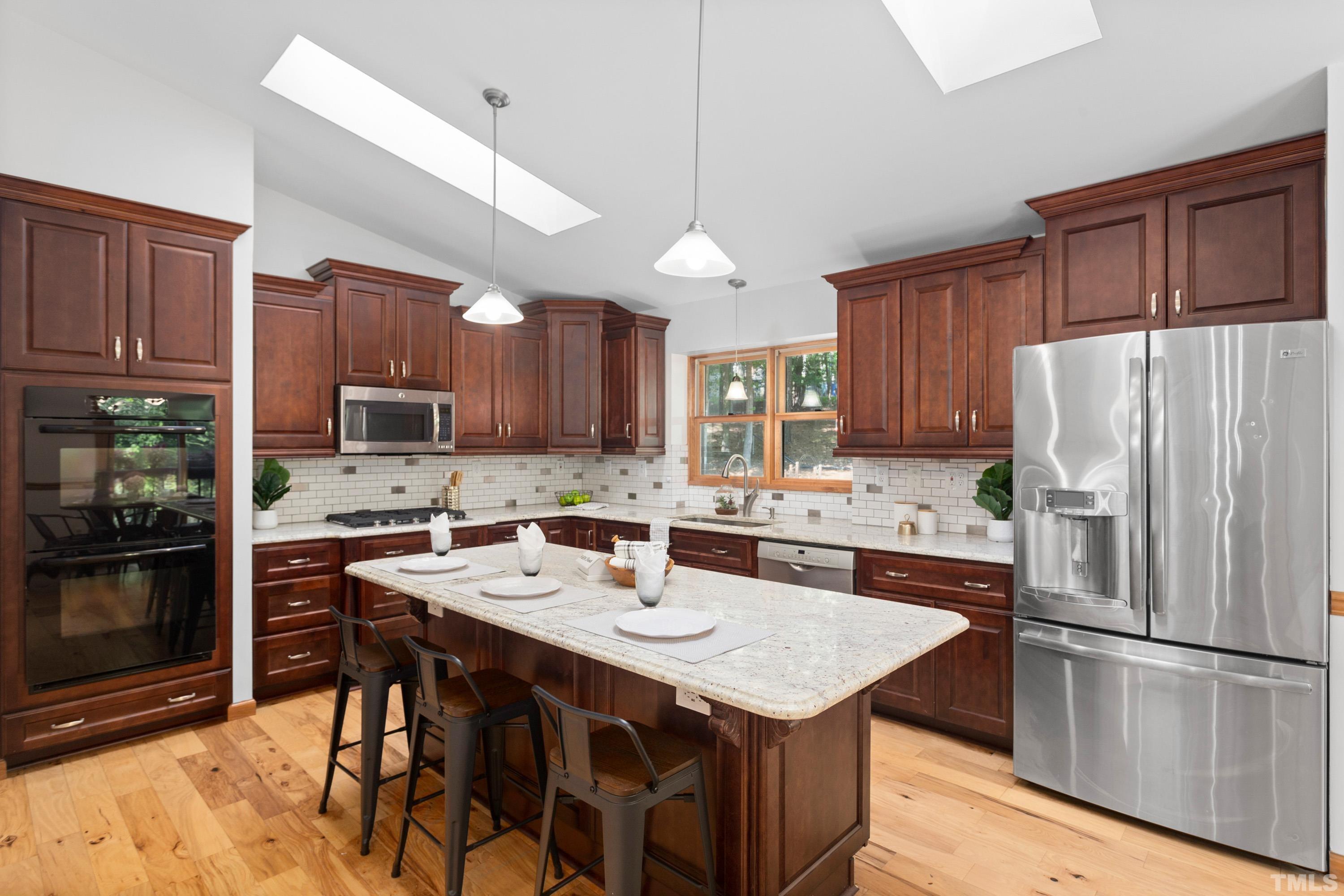 2600 Ferrand Drive Durham, NC 27705 - Photo 10 of 67 a kitchen with stainless steel appliances granite countertop a refrigerator a stove a sink a dining table and chairs with wooden floor
