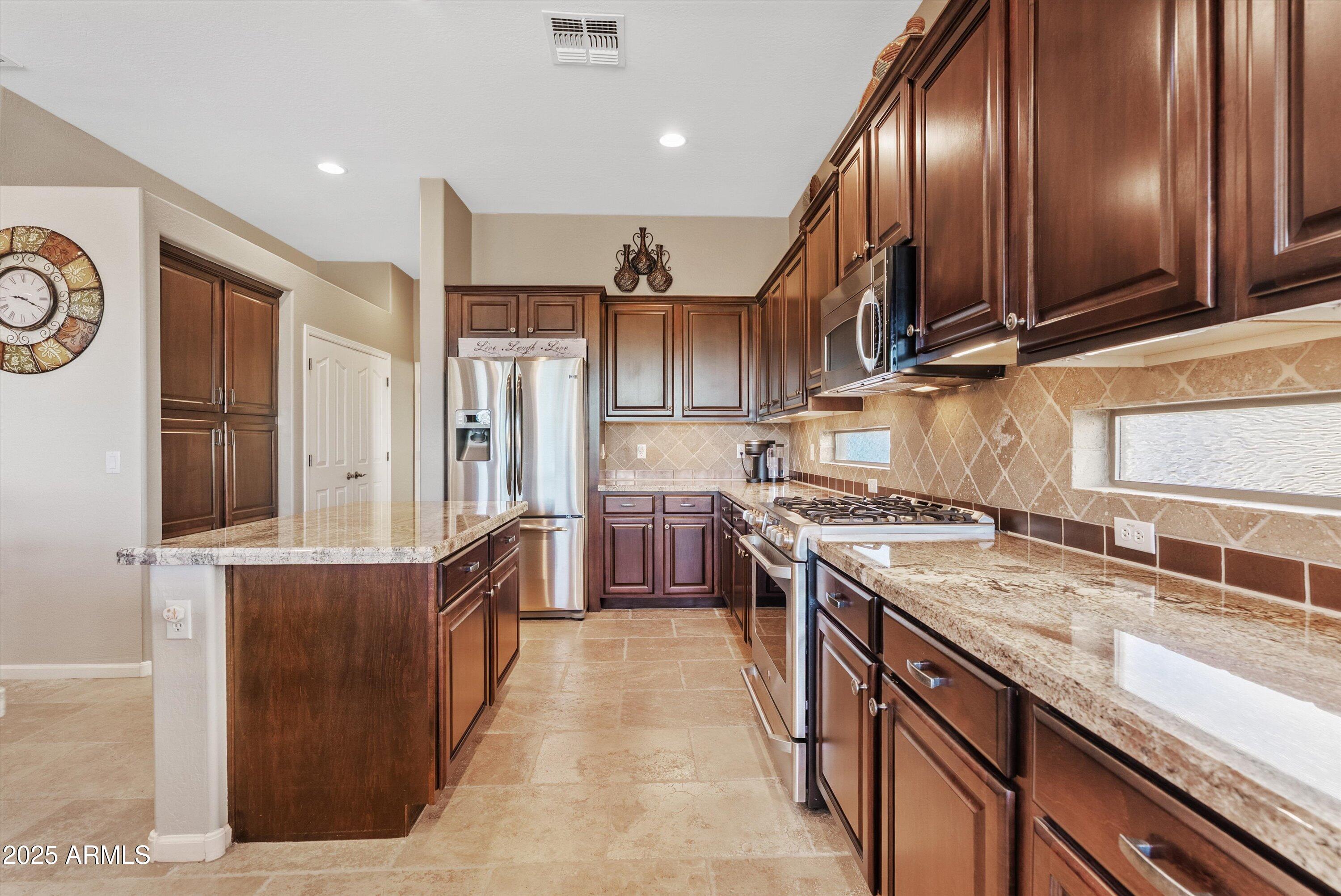6805 Rachael Way Gilbert, AZ 85298 - Photo 10 of 50 a kitchen with stainless steel appliances granite countertop a sink a stove and a refrigerator