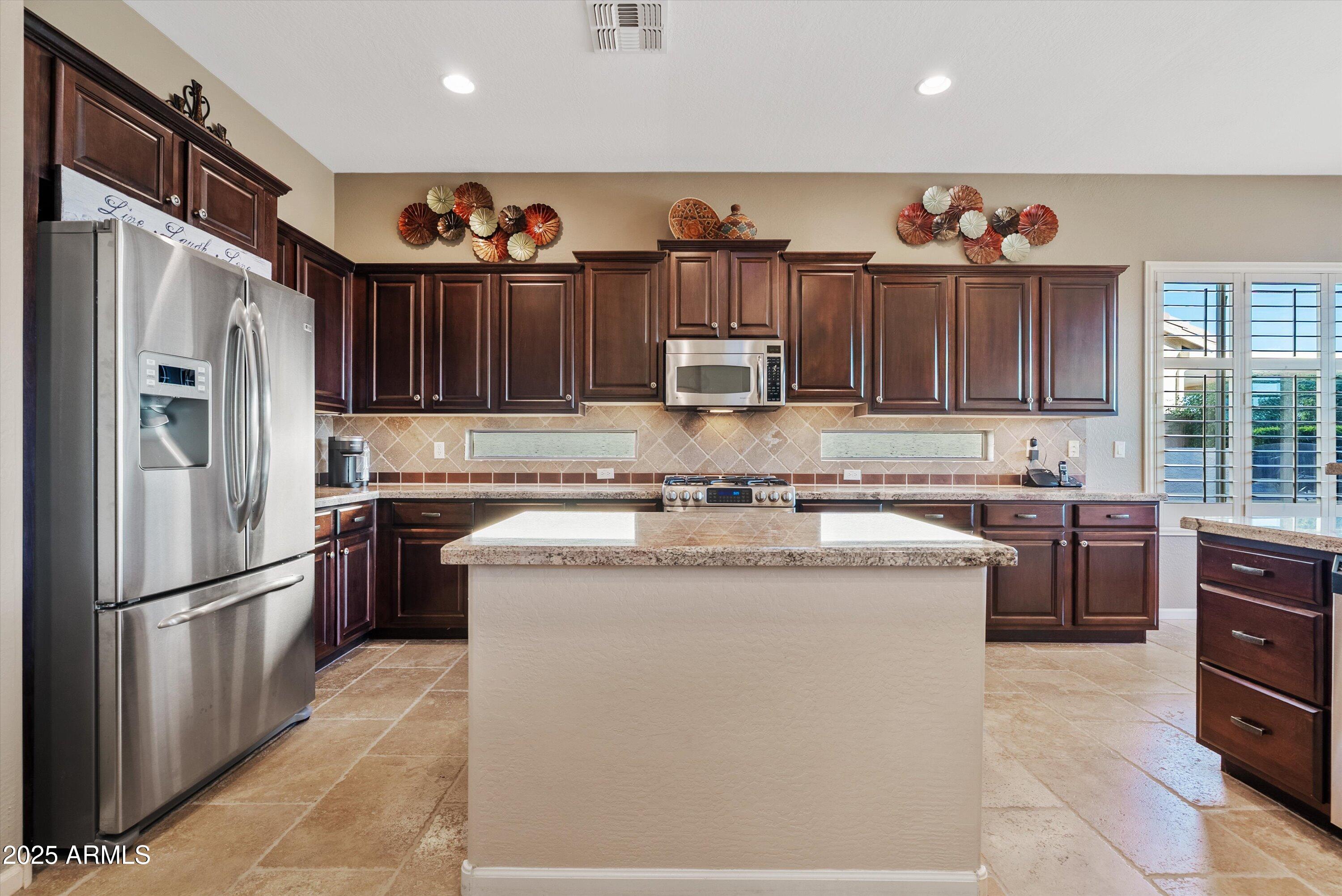 6805 Rachael Way Gilbert, AZ 85298 - Photo 15 of 50 a kitchen with stainless steel appliances granite countertop a refrigerator sink and stove
