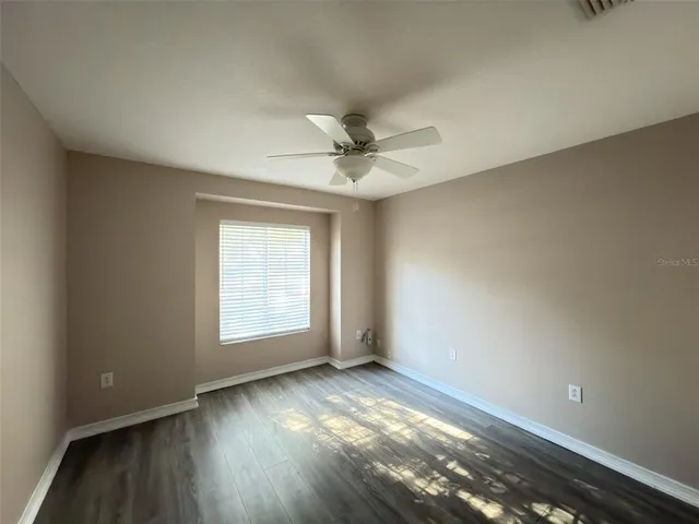 an empty room with a window and a ceiling fan