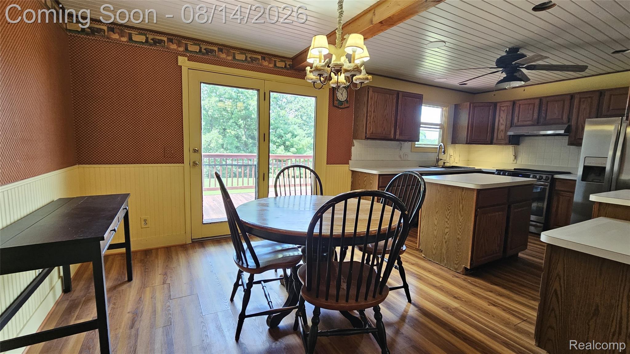 7966 Pettysville Road Pinckney, MI 48169 - Photo 7 of 43 Open-concept kitchen and dining area featuring wood-finish flooring, warm earth-tone walls with wainscoting, and a sliding glass door providing natural light