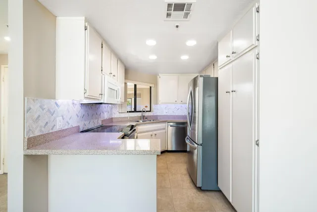 a kitchen with white cabinets and white appliances