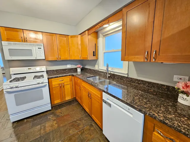 a kitchen with granite countertop a sink stove and cabinets