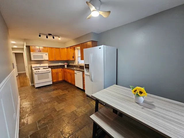 a kitchen with stainless steel appliances a stove refrigerator dining table and chairs