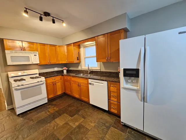 a kitchen with granite countertop white cabinets and white appliances