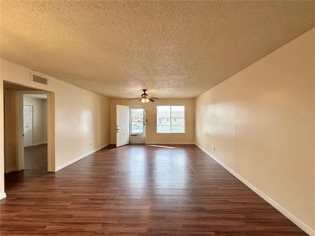 a view of an empty room with window and wooden floor