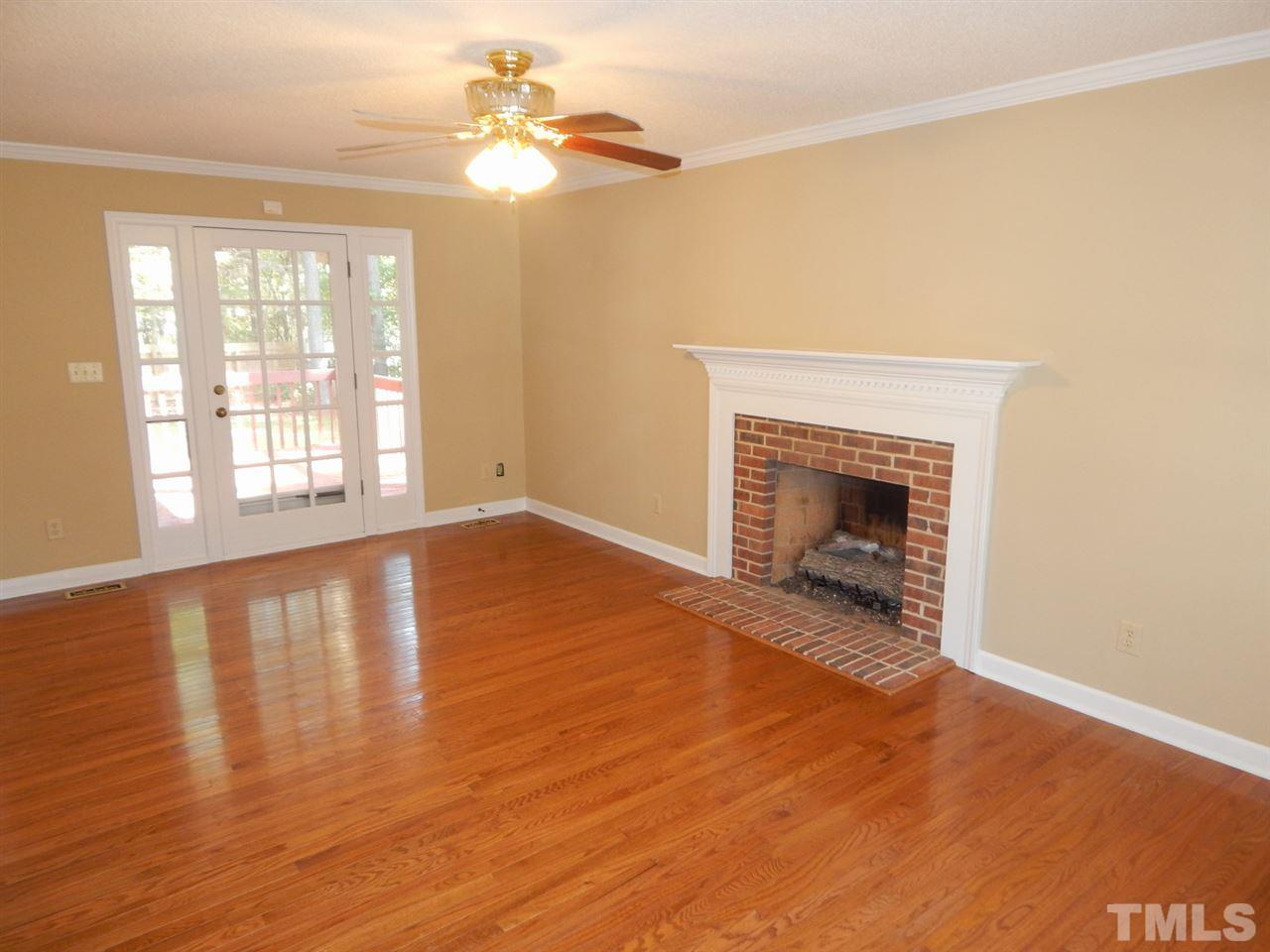 4829 Draper Road Raleigh, NC 27616 - Photo 2 of 25 an empty room with wooden floor fireplace and windows