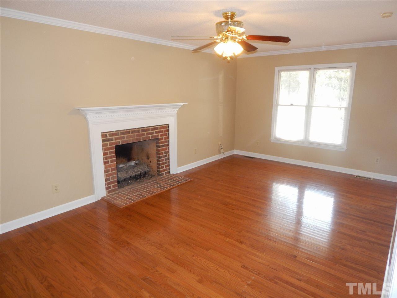 4829 Draper Road Raleigh, NC 27616 - Photo 6 of 25 an empty room with wooden floor chandelier fan and windows