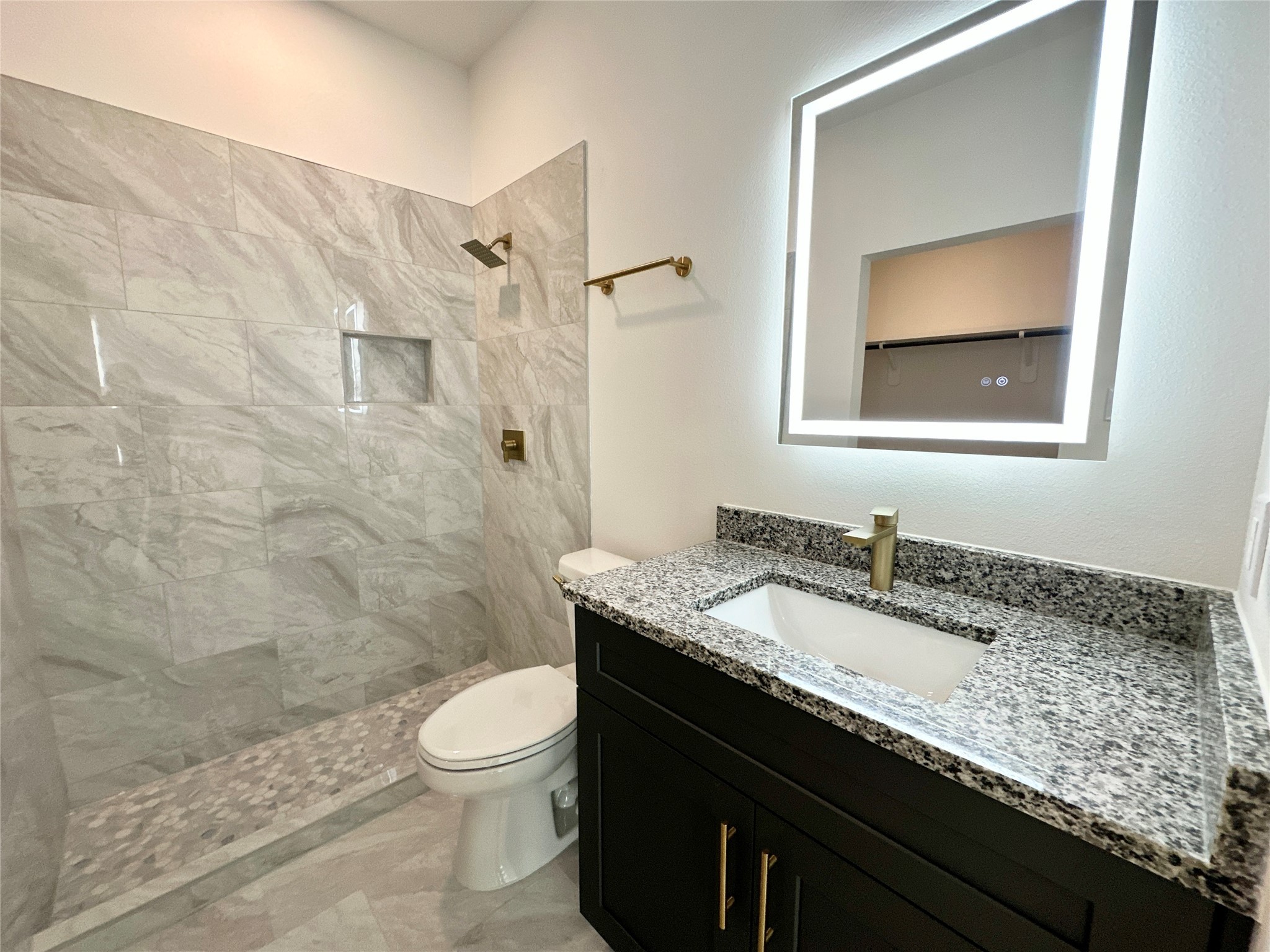 11563 Persimmon Street Willis, TX 77318 - Photo 11 of 19 a bathroom with a granite countertop sink toilet a mirror and shower