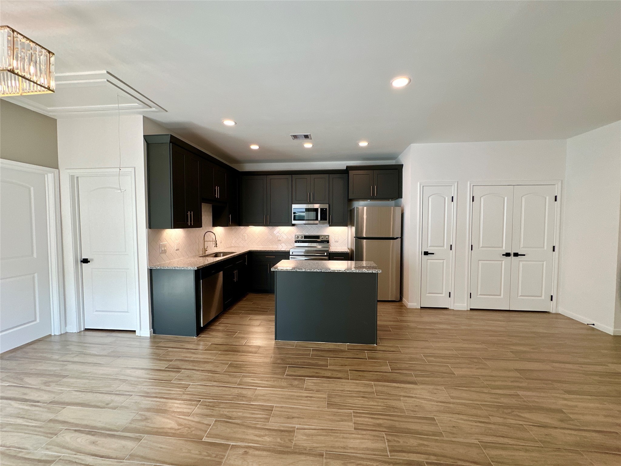 11563 Persimmon Street Willis, TX 77318 - Photo 4 of 19 a kitchen with stainless steel appliances kitchen island granite countertop a refrigerator and a sink