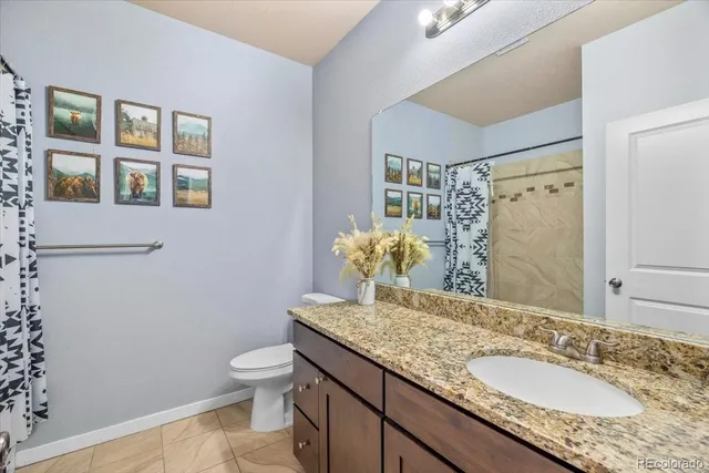 a bathroom with a granite countertop sink a toilet and mirror