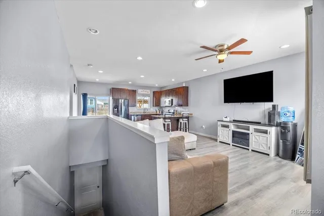 a living room with stainless steel appliances kitchen island furniture and a flat screen tv