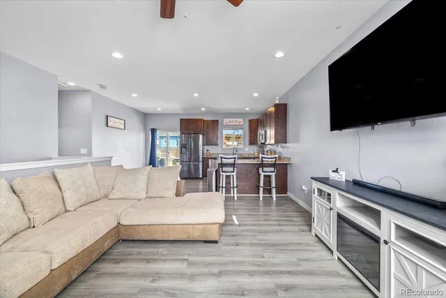 a living room with stainless steel appliances furniture and a flat screen tv