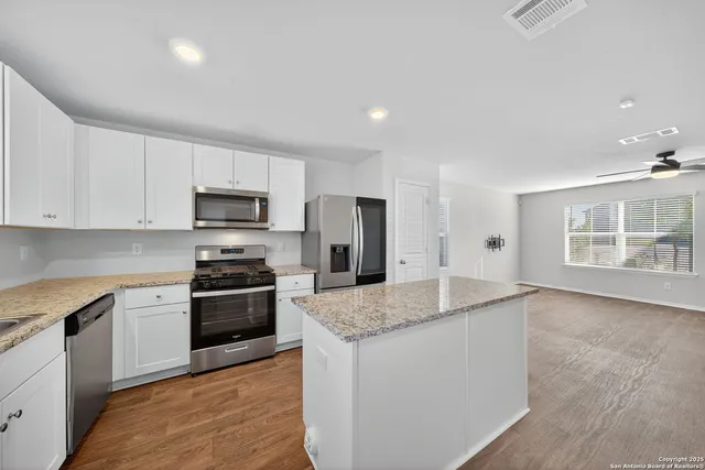 a kitchen with stainless steel appliances granite countertop a stove a sink and a refrigerator