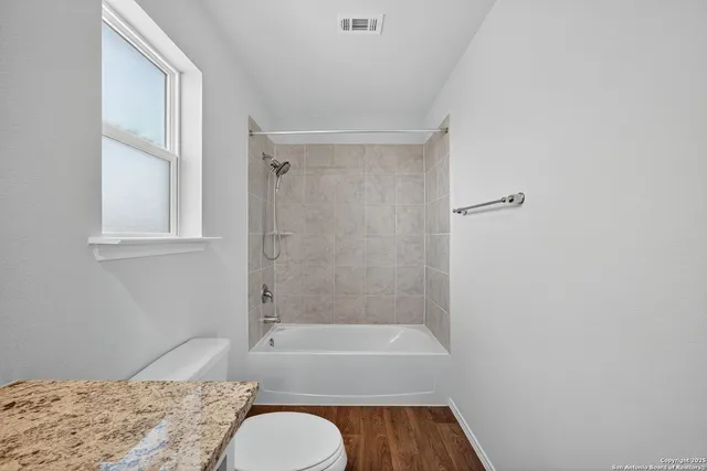 a bathroom with a granite countertop bathtub shower and toilet